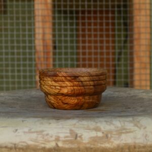 A hand-crafted pinch bowl made from reclaimed California olive wood with horizontal accents around the rim and finished with food-safe, non-toxic oil.